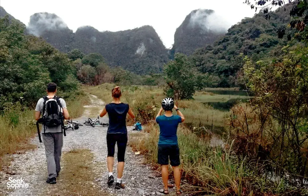 Guided cycling in Borneo’s countryside near Kuching, with cyclists on a gravel track through a lush valley