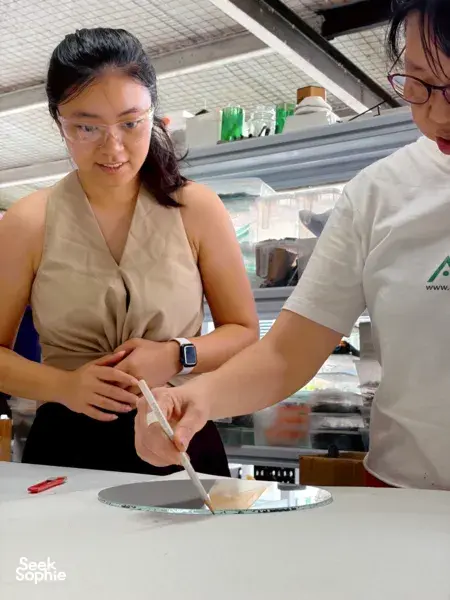 Instructor and guest in protective eyewear shaping glass on a table at Art Glass Centre, Singapore