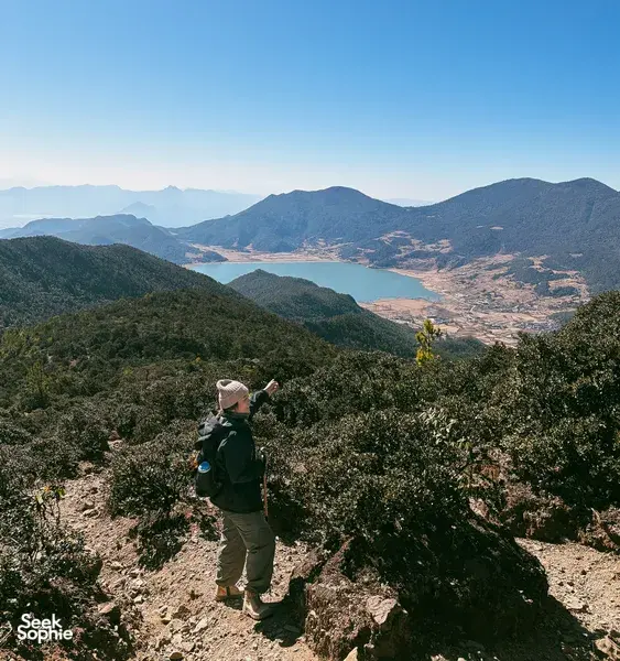 Hiker stands on a high ridge above the valley near Jade Dragon Snow Mountain in Lijiang, guided hike with The Bivou Lijiang
