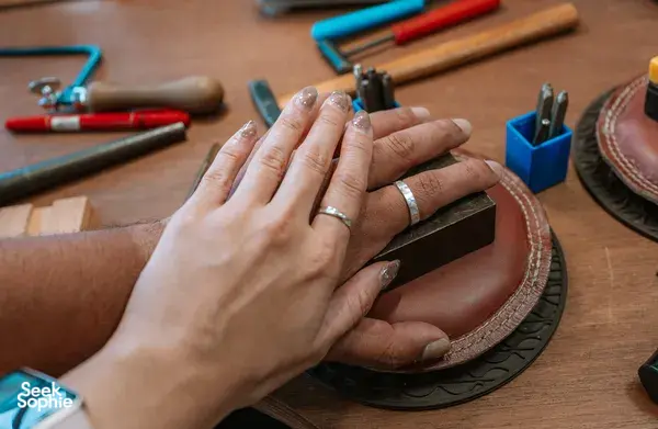 Hands fitting matching rings in a couple ring-making session at Fat Anvil Studios studio bench in Singapore