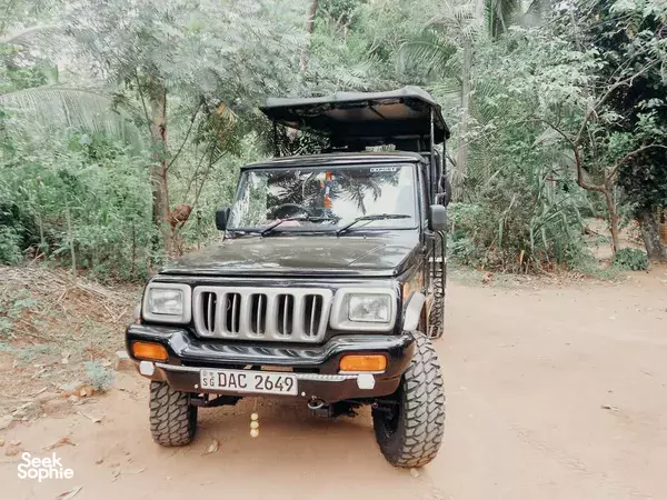 Safari jeep on a dusty track through woodland on Udawalawe National Park safari arranged by Splendid Lake View Safari Lodge