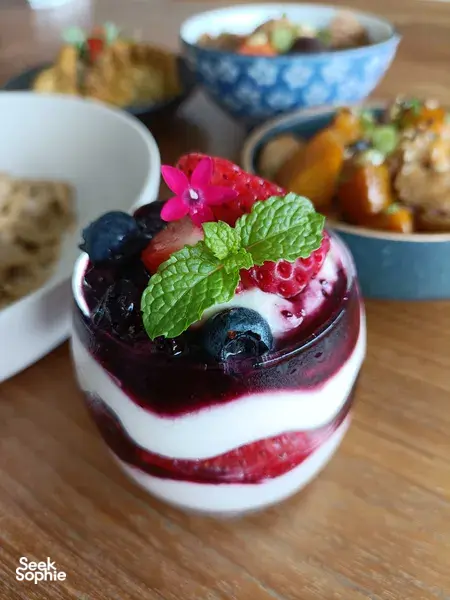 Layered berry and cream dessert in a glass with mint and flowers for TCM-inspired teatime in Singapore, hands-on workshops in Singapore