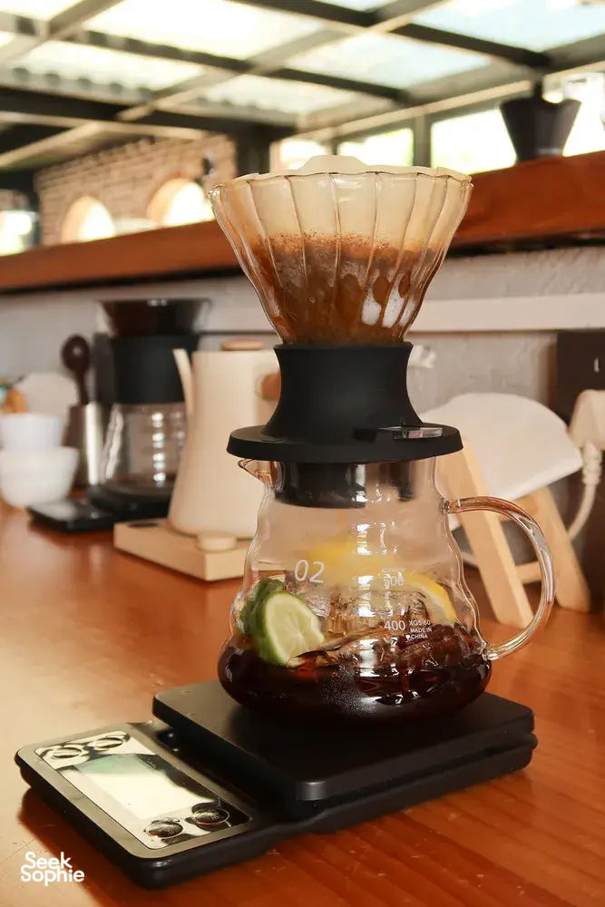 Carafe of brewed coffee with a pour-over dripper and a tasting card on the counter in a Lijiang specialty coffee workshop