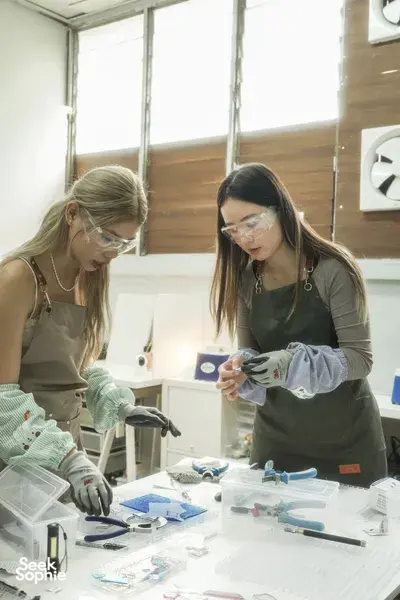 Gloved makers cutting and fitting stained-glass pieces on a work table for suncatcher craft workshops in Singapore