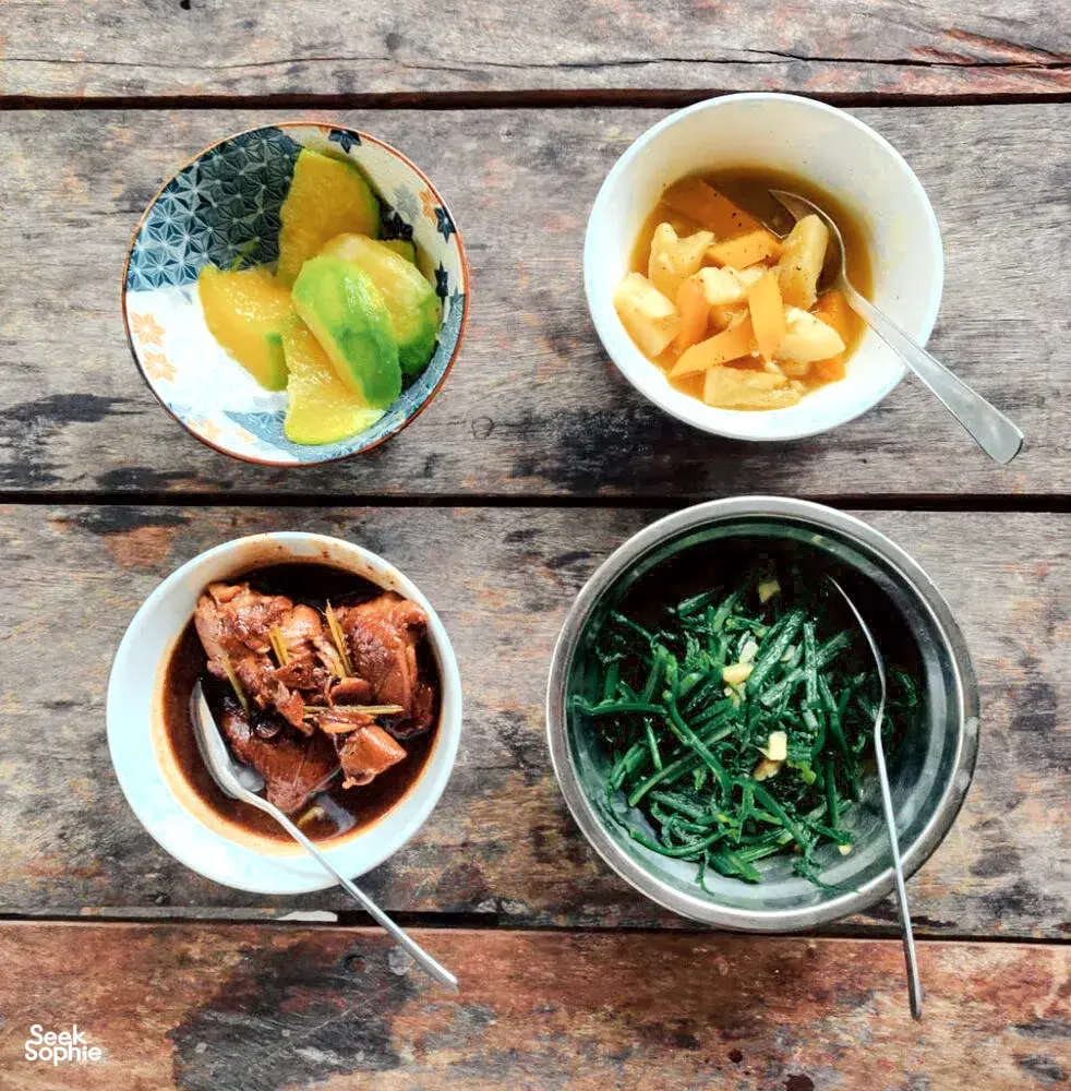 Bowl of fruit, leafy greens and soup plated on a wooden table at Ngapuh Homesteadβs regenerative homestead near Kuching