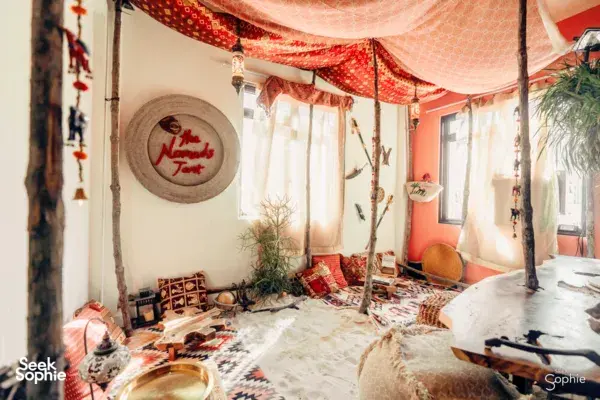 Cosy decorated guest room with bed canopy, patterned textiles and plants at The Unexpected’s space in Singapore, workshops in Singapore