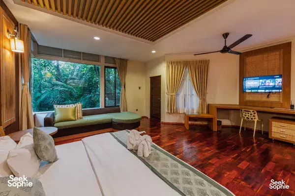 Bedroom scene with a daybed, window curtains and green foliage views at Kinabatangan Wetlands Resort in Sandakan on the Kinabatangan River
