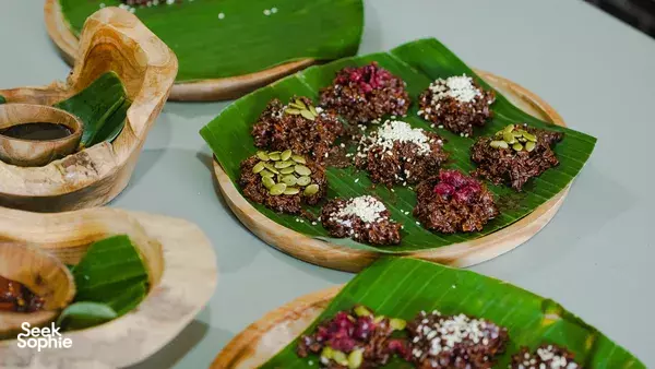 Plates of tempe cookies on banana leaves—topped with sesame and crunchy bits—prepared for a traditional tempe making experience in Bali