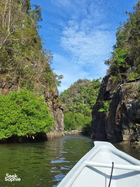 Bow view from a boat gliding through rocky green mangroves in Kilim Geoforest, Langkawi on Dev's Adventure Tours cruise