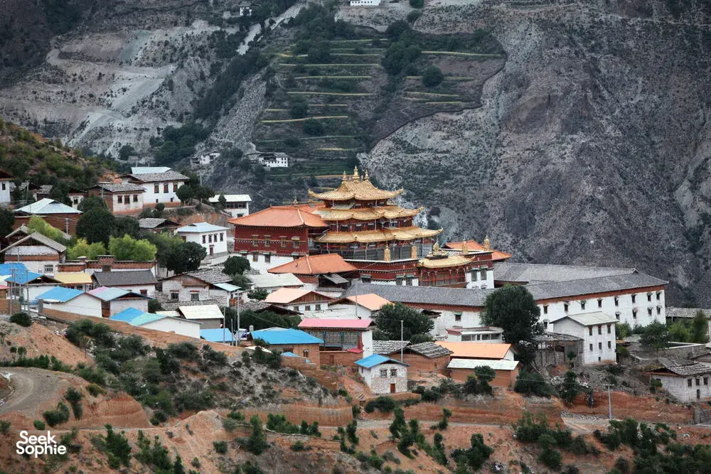 Terraced hillside village with multi-building Tibetan monastery complex and prayer halls in Shangri-La’s Meili region