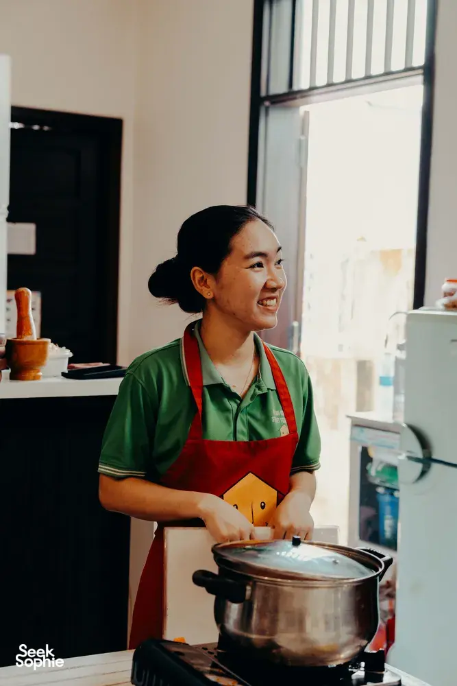 在越南会安的 Jolie 烹饪课上，Jolie 在家中厨房里搅拌锅中的食材