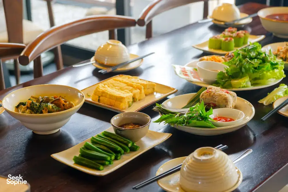 Vietnamese meal spread with bowls, greens, and tofu on a table for an agarwood tour tasting dinner in Hanoi