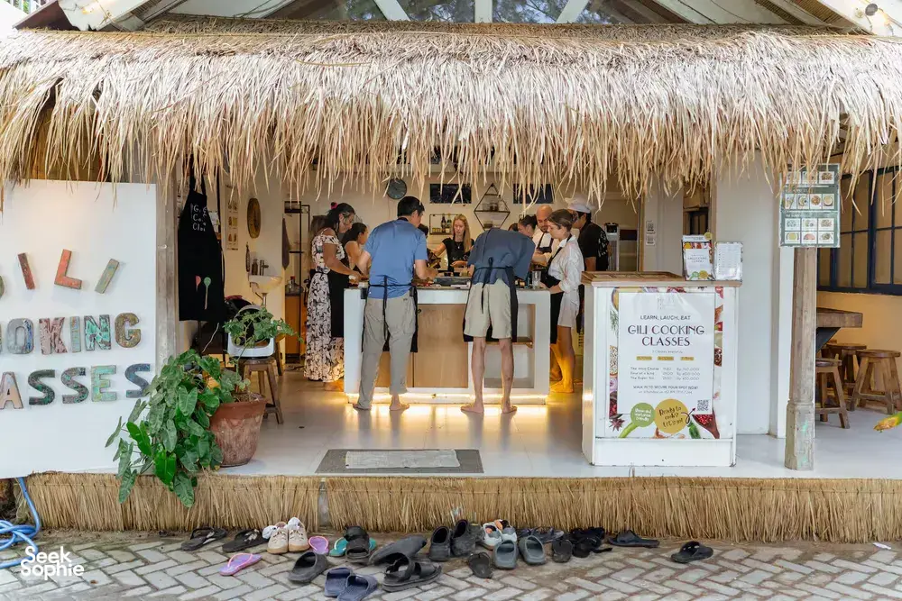 Thatched-roof entrance of Gili Cooking Classes on Gili T, Lombok, with signage and people waiting for the cooking class