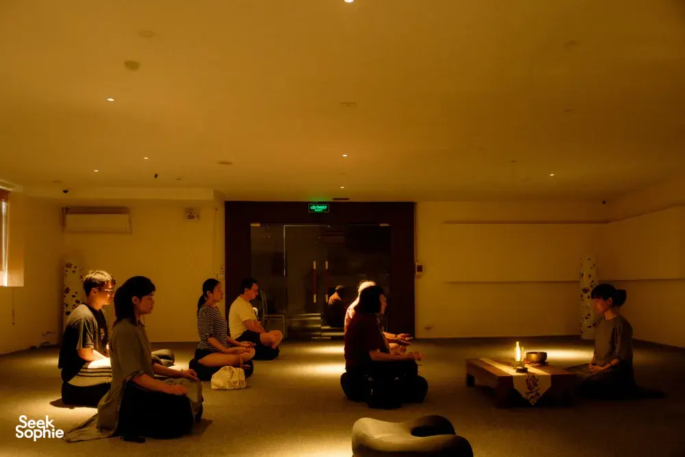 Travellers sit on floor cushions in a candle-lit room for a calm incense tasting during a rare agarwood tour in Hanoi