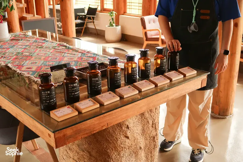Specialty coffee bottles and sample cartons displayed on a wooden table at Seeker Yunnan Coffee Estate in Lijiang