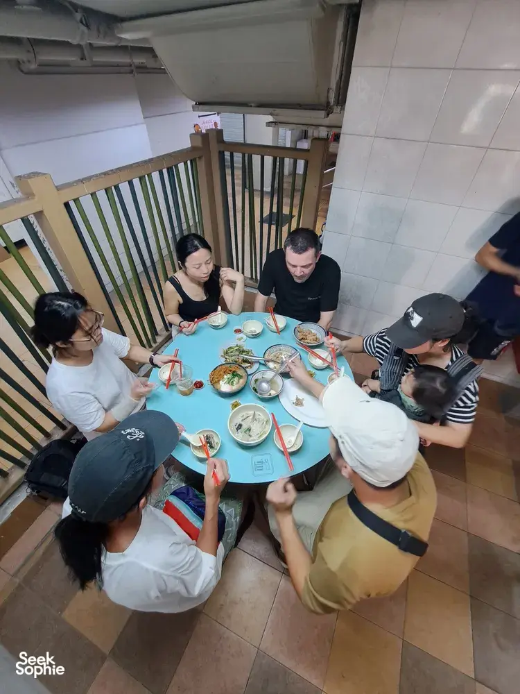 Group gathered around a table of Cantonese seafood dishes during a Chinatown hawker experience in Singapore