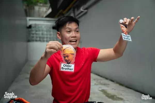 Smiling participant holds snack packages during a stop on a guided hike around Mount Faber, Singapore