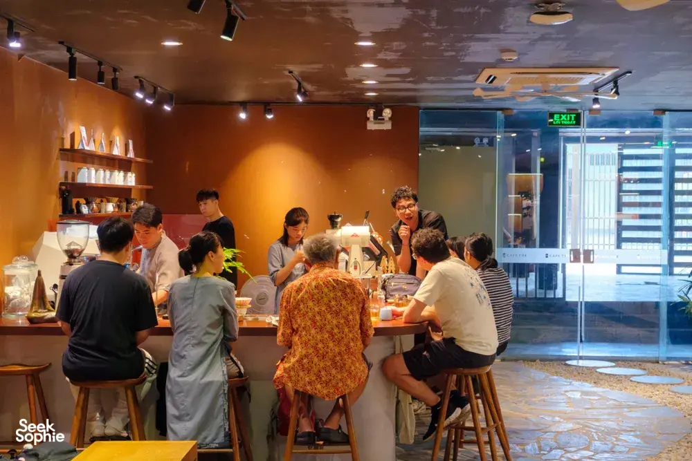 Group gathered around tables as a guide explains rare agarwood scent in the workshop café in Hanoi, Vietnam