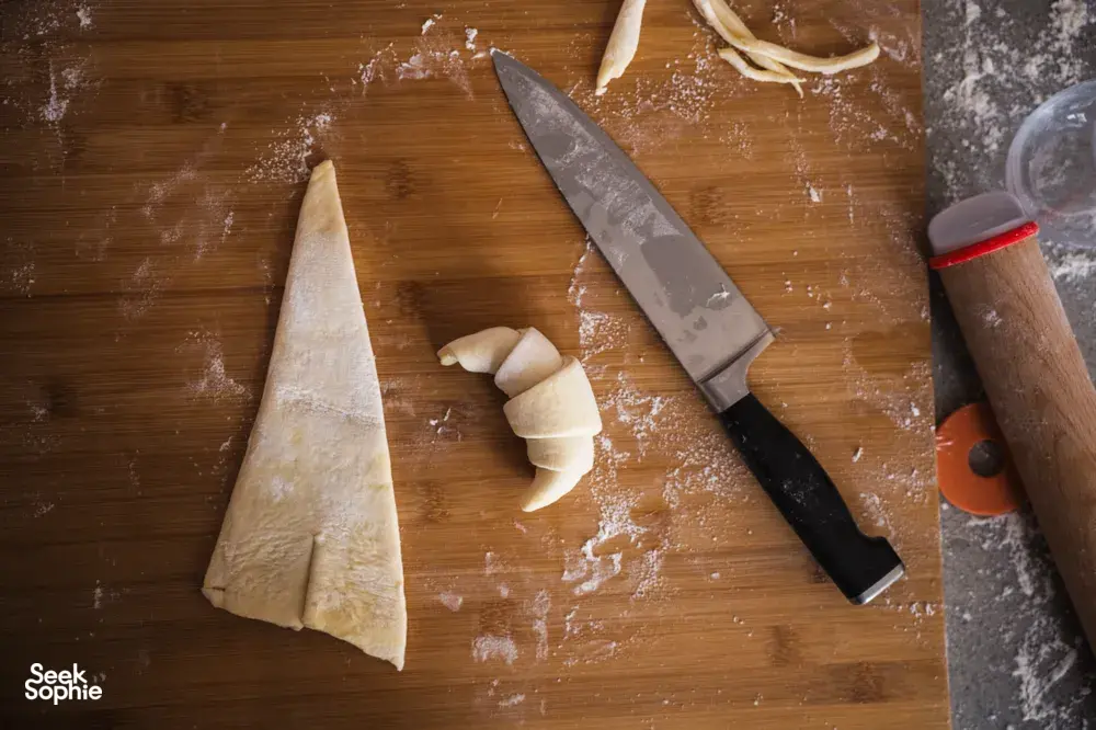 Floured wooden board with cut croissant dough pieces and a chef’s knife during croissant prep at French Cooking Lab in Singapore