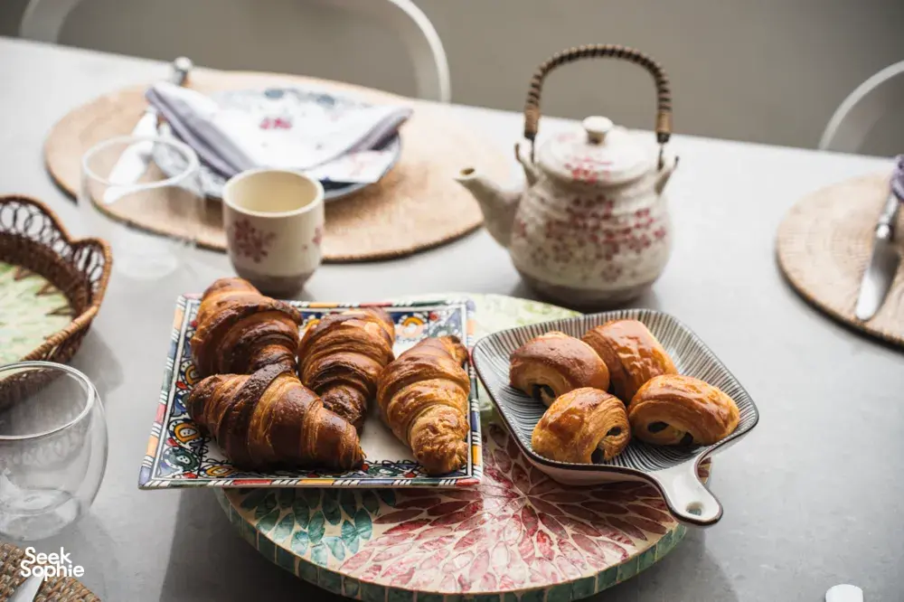 Croissants on a patterned platter with teapot and cups on a dining table at French Cooking Lab in Singapore