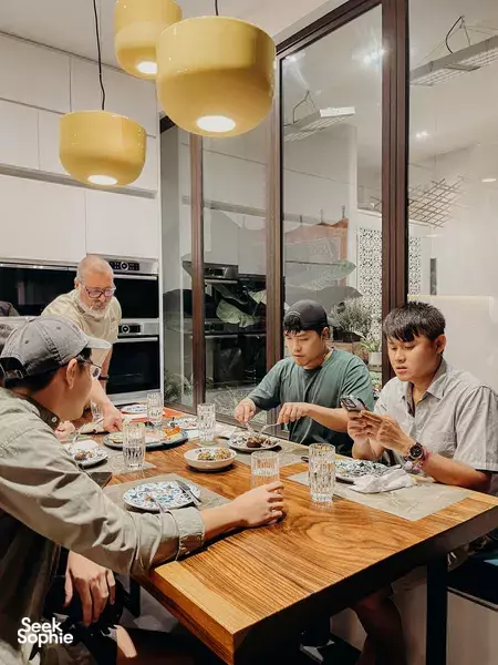 Diners gathered around a wooden table by an oven in a renovated Peranakan shophouse for private dining Singapore