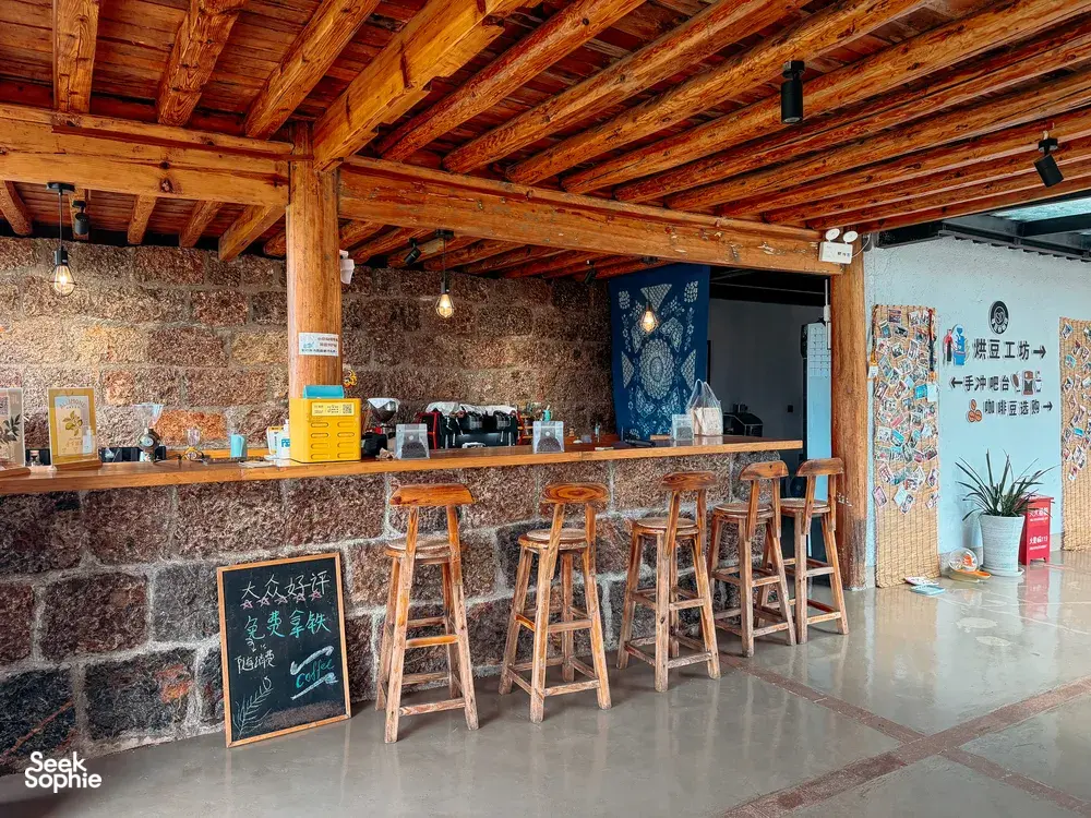 Wooden guest counter with bar stools and a chalkboard menu at Seeker Yunnan Coffee Estate, a family-run coffee workshop in Lijiang