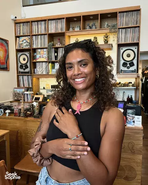 Curly-haired woman smiling in a studio, wearing a starfish pendant necklace from a creative workshop in Khao Lak
