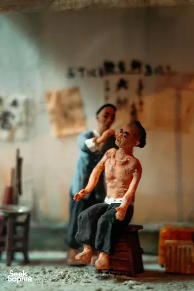 Triad Trails ex-gangster exhibit: seated bare-chested figure in a dim room with another man behind, Singapore hidden gems