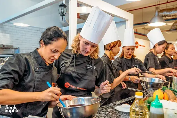 Students in chef hats stir batter in stainless-steel bowls during a hands-on baking workshop in Singapore, workshops in Singapore