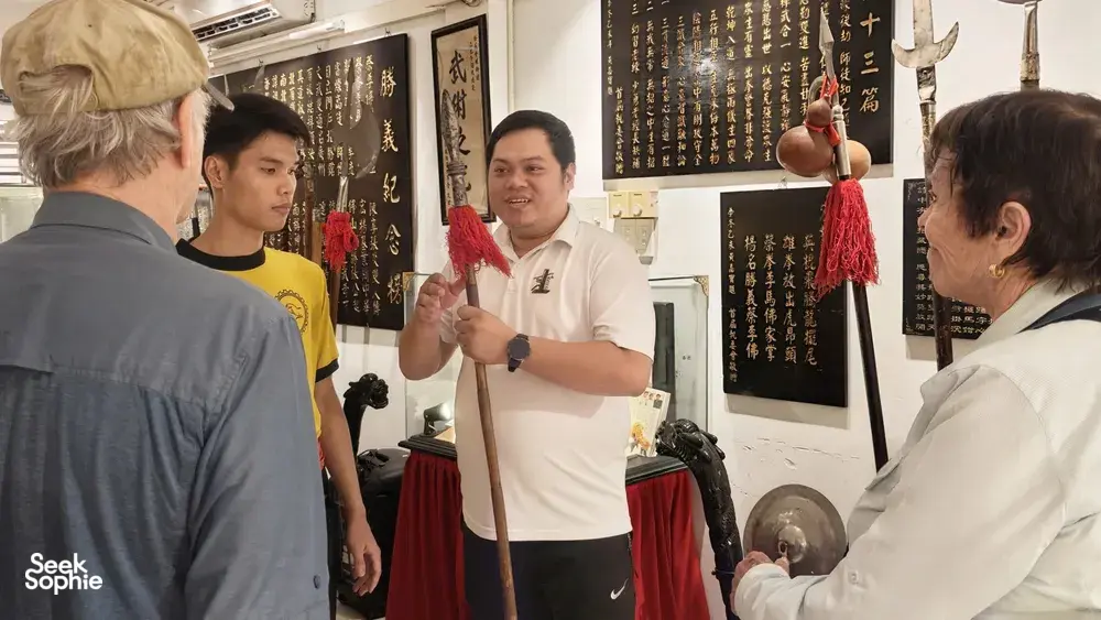 Martial arts class in Ho Chi Minh City Lion Dance heritage room, as a guide holds a wooden staff and demonstrates to guests