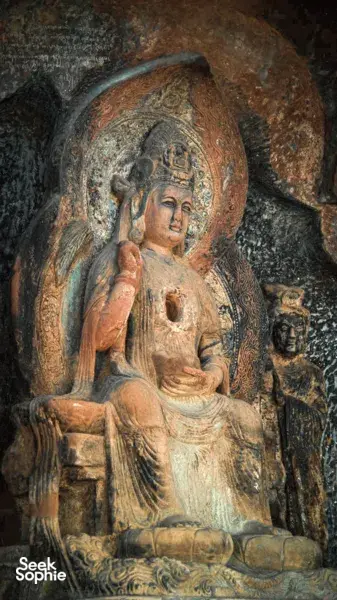 Close-up patung Buddha duduk berwarna di dalam dinding gua batu, gua Buddha Shaxi di eco retreat Dali