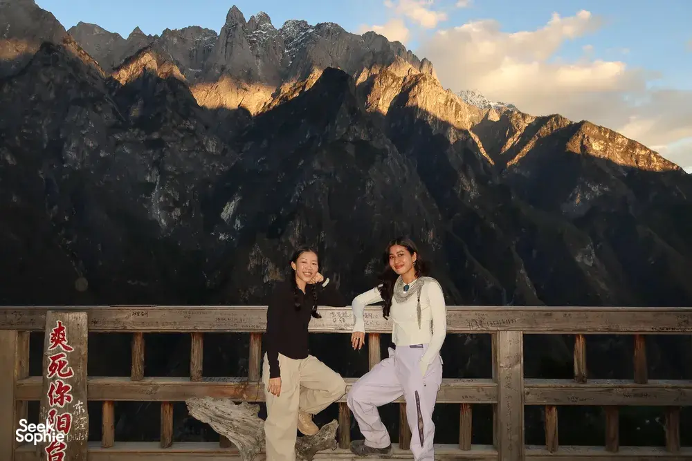 Hikers posing by a wooden viewing deck with rugged peaks above Tiger Leaping Gorge near Lijiang at sunset on a 2D1N high trail
