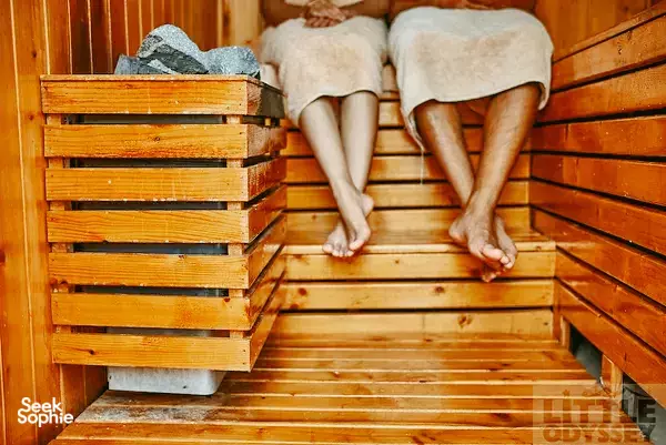 Wooden sauna benches at The Island Lodge, Mekong Delta resort, with two guests relaxing in towels on the warm timber slats