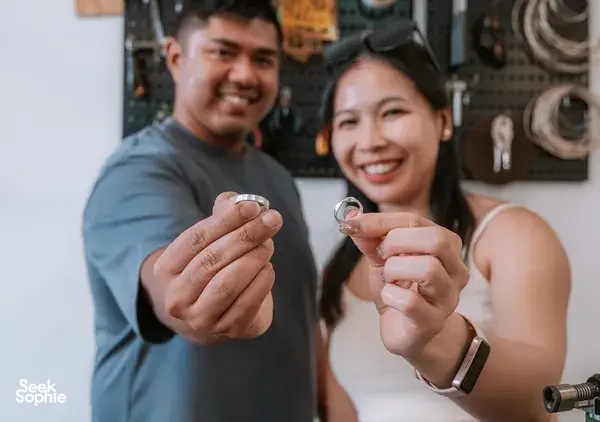 Guests smiling while holding handmade silver couple rings in the workshop at Fat Anvil Studios in Singapore, workshops in Singapore