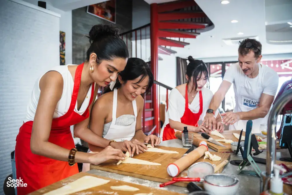Hands shaping croissant dough on wooden boards in a Singapore kitchen with a French Cooking Lab group, workshops in Singapore