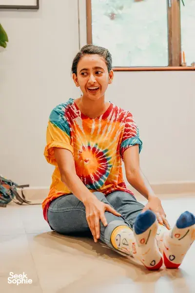 Shanice Stanislaus clowning workshop, kneeling beside painted clown socks during improvisation for team building Singapore