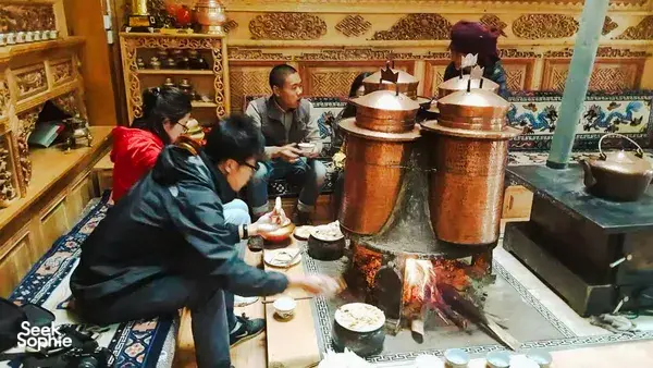 Warm Tibetan kitchen cooking over copper pots and an open flame at a home lunch in Shangri-La, host-led experience