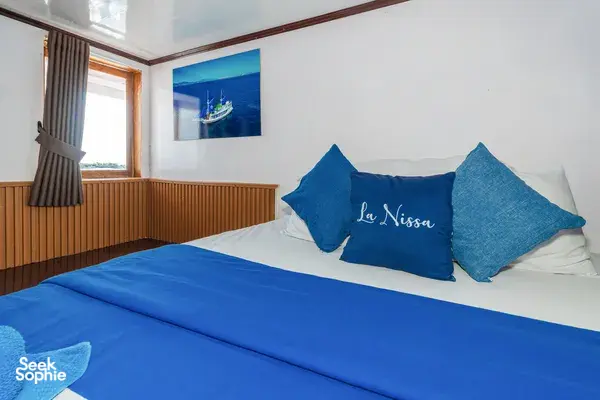 La Nissa printed on blue cabin pillows, in a Komodo boat trip cabin in Labuan Bajo with a large wall window