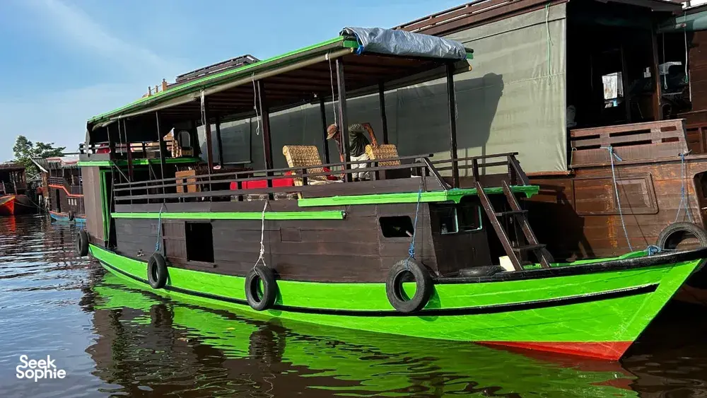 Green small boat moored at Pangkalan Bun for a 3D2N couples cruise with Sister Tour on a calm river, Tanjung Puting