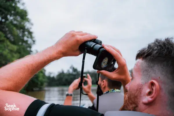 Wildlife spotting on the Kinabatangan River as a guest films through a smartphone from a safari boat near Sukau Greenview Lodge