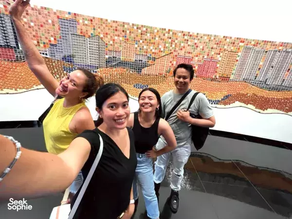 Friends pose on a rooftop terrace with a colourful tiled mural wall during a Singapore team challenge — team building Singapore