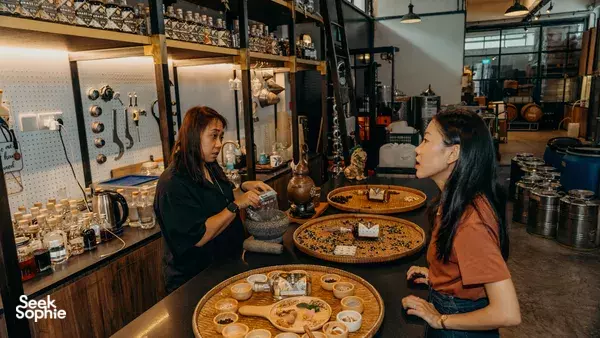Participants mixing gin at a counter in Brass Lion Distillery, with copper tools and shelves of botanicals—workshops in Singapore