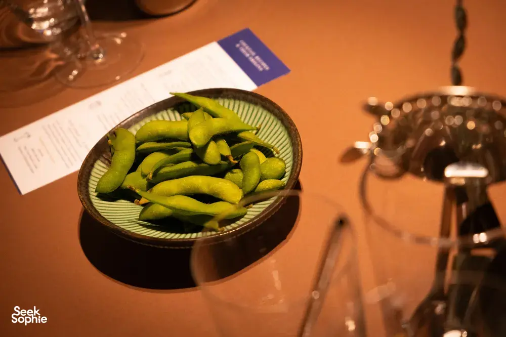 Close-up of green chillies served with cocktail menus and glassware on a table at an intimate Singapore bar