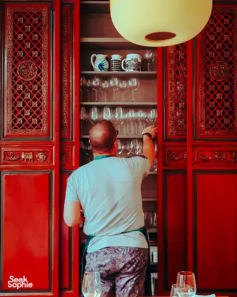 Host reaching for glassware inside a Peranakan shophouse for a Mediterranean 5-course dinner in Singapore private dining Singapore