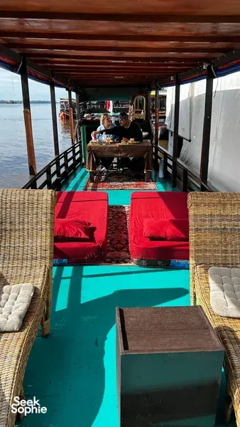 Onboard dining set-up with cushioned seating and a table on a green small boat, for a 3D2N Tanjung Puting cruise for couples.