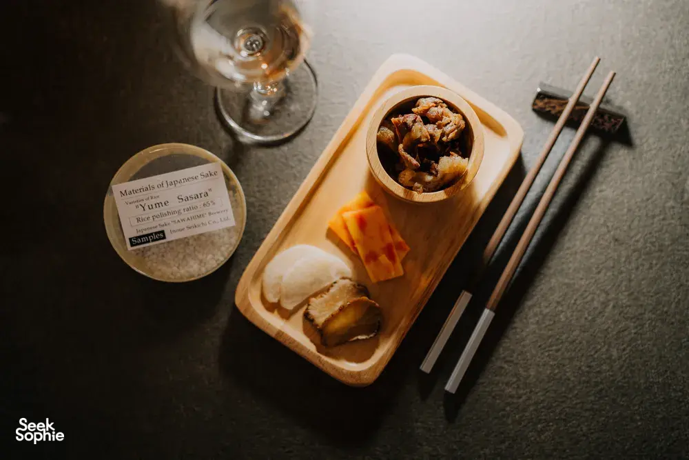 Rare sake tasting spread in a tucked-away Singapore shop with small pour glasses, appetisers and chopsticks on a tray — SakeMama
