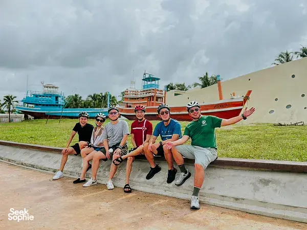 Cyclists in helmets posing at Takua Pa Old Town harbour in Khao Lak during a private, community-focused cycling trip
