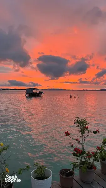Sunset from a Semporna water bungalow deck, sea and floating hut in view, with Bigfin Divers stay over the bay