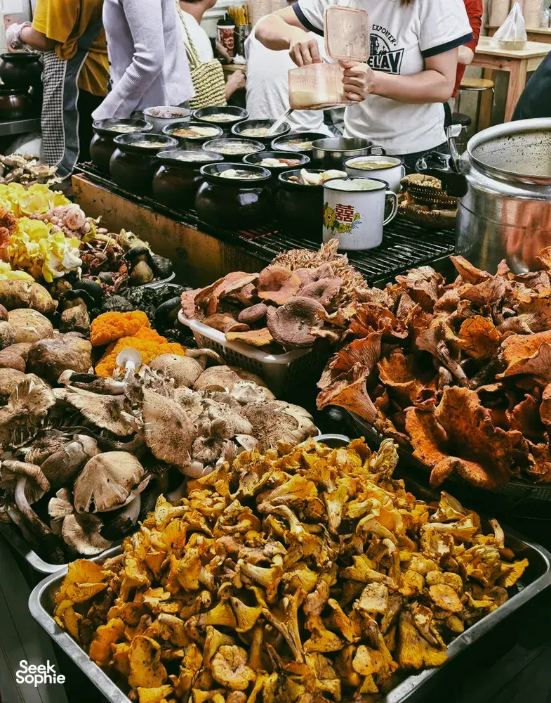 Lijiang street food stall with trays of grilled and spiced dishes and paper cups, as part of a local stories food hunt