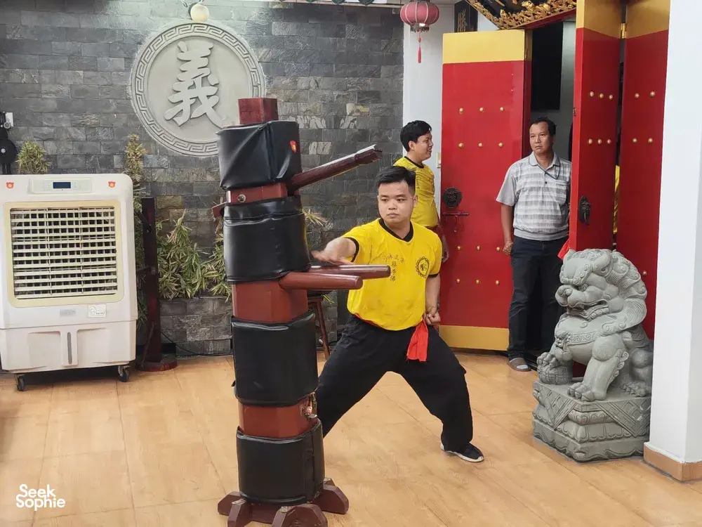 Kung fu trainees practising stances with lion-dance drums in an indoor Chinatown hall in Ho Chi Minh City